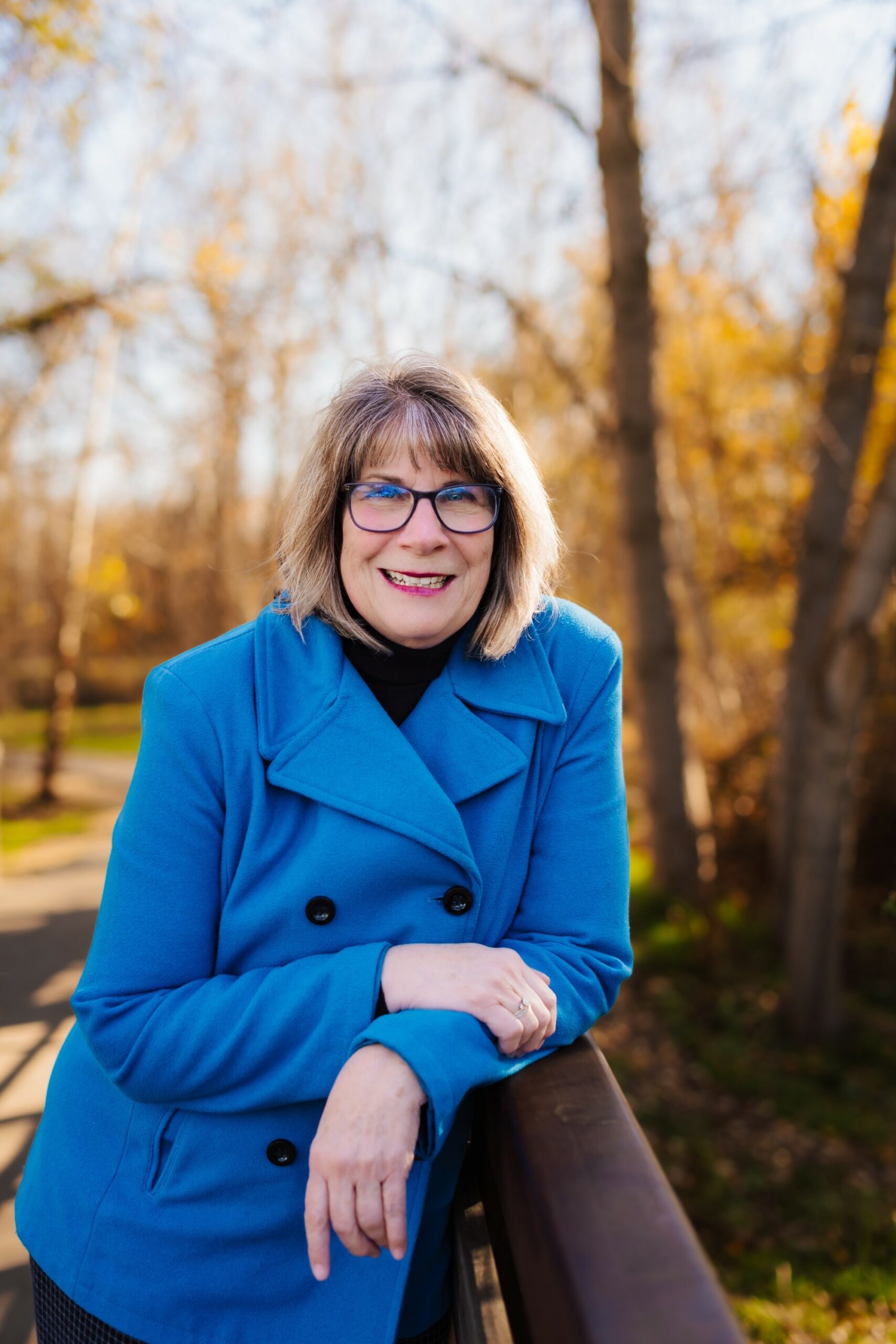 Val Gray standing next to a tree with a blue coat on